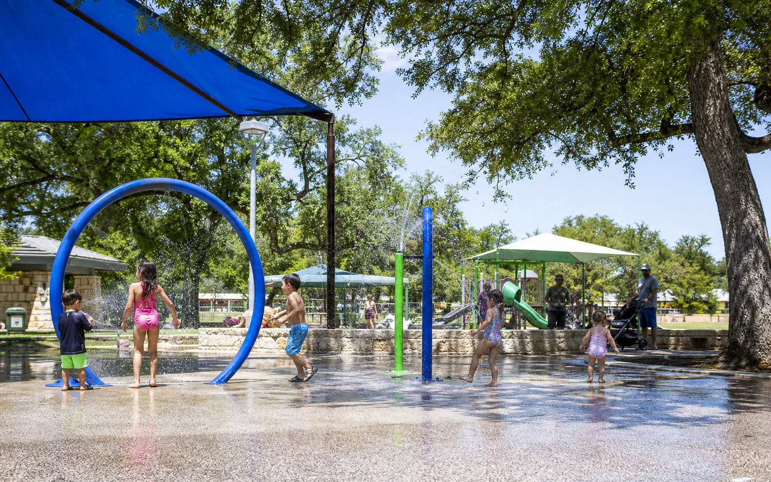 Children playing at a shaded New Braunfels splash pad and public park